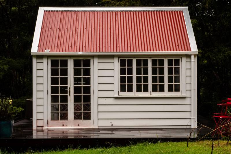 A small white weatherboard cottage with a red iron roof in Northland