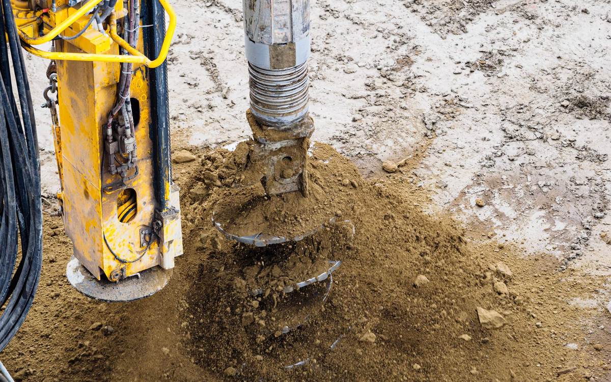 A helical auger turning into the ground under a hydraulic drive head